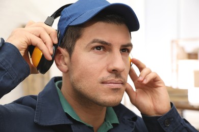 Worker wearing safety headphones indoors. Hearing protection device