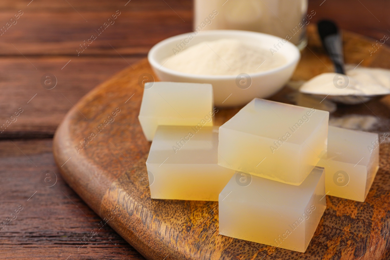 Photo of Agar-agar jelly cubes and powder on wooden table, closeup. Space for text