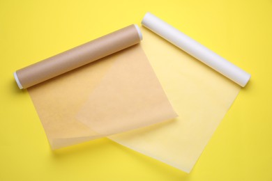 Photo of Rolls of baking paper on yellow background, top view