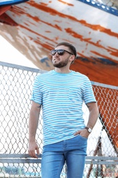 Photo of Young hipster man in stylish jeans on pier