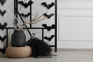 Photo of Paper bats and festive decor near white wall, space for text. Halloween celebration