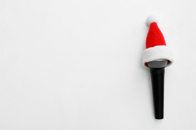 Photo of Top view of microphone with Santa hat on white table, space for text. Christmas music
