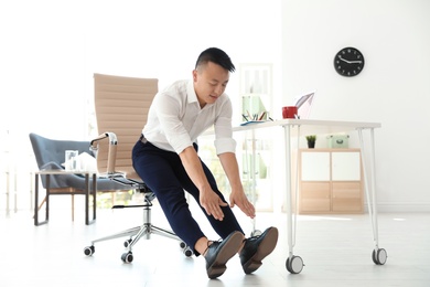 Photo of Young businessman stretching in office. Workplace fitness