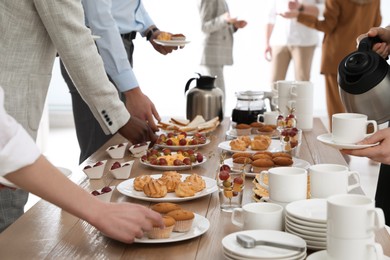 Photo of People near table with different delicious snacks during coffee break, closeup