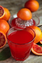 Photo of Tasty sicilian orange juice in glass and fruits on wooden table