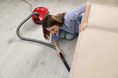 Young woman using vacuum cleaner at home