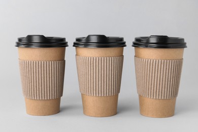 Photo of Paper cups with black lids on light grey background. Coffee to go