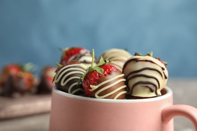 Photo of Cup with chocolate covered strawberries on table, closeup
