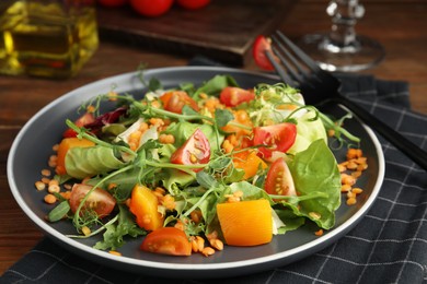 Photo of Delicious salad with lentils and vegetables served on wooden table, closeup