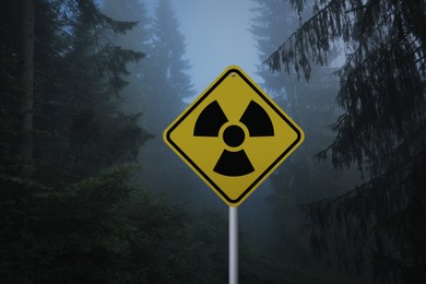 Image of Radioactive pollution. Yellow warning sign with hazard symbol in forest