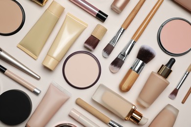 Photo of Face powders and other makeup products on beige background, flat lay