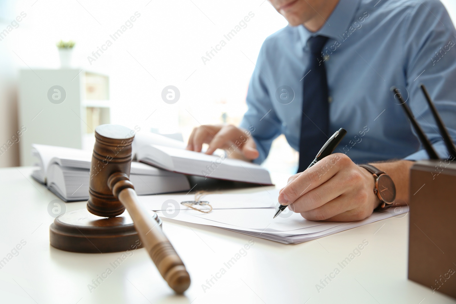 Photo of Notary working with papers and judge gavel on table, closeup. Law and justice concept