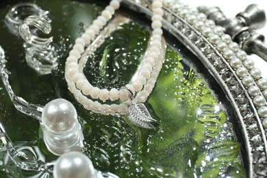 Photo of Elegant jewelry with water drops on vintage mirror, closeup