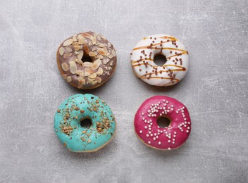 Photo of Different tasty glazed donuts on light grey table, flat lay