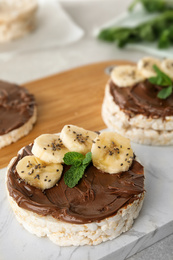 Photo of Puffed rice cakes with chocolate spread, banana and mint on board, closeup