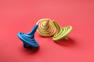 Photo of Many colorful spinning tops on red background, closeup