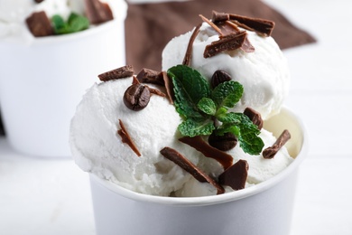 Photo of Yummy ice cream with chocolate in paper cup, closeup