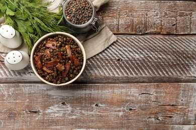 Photo of Delicious lentils with bacon, dill and parsley on wooden table, top view. Space for text