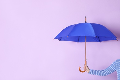 Person holding bright open umbrella on color background with space for design