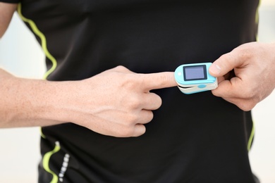 Photo of Young man checking pulse after workout, focus on hands