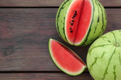 Photo of Different delicious ripe watermelons on wooden table, above view. Space for text