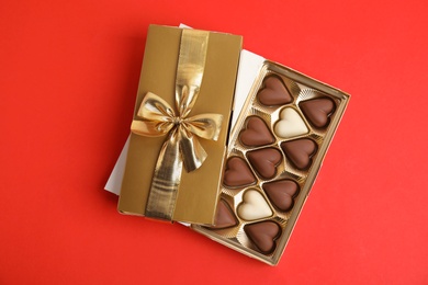 Photo of Tasty heart shaped chocolate candies on red background, top view. Happy Valentine's day