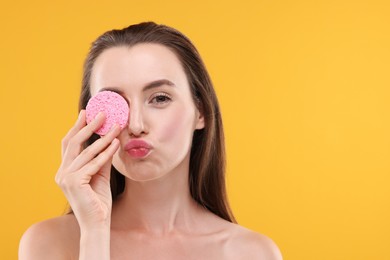 Photo of Happy young woman holding face sponge on orange background. Space for text