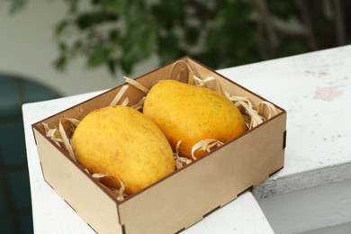 Photo of Delicious ripe yellow mangoes in wooden box outdoors
