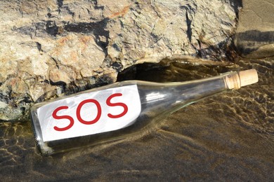 Photo of Glass bottle with SOS message near sea rock