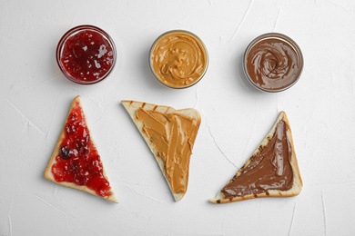 Photo of Slices of bread with different spreads on white table, flat lay