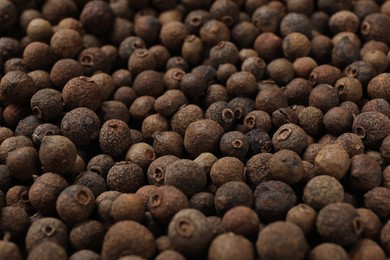 Photo of Aromatic allspice pepper grains as background, closeup view