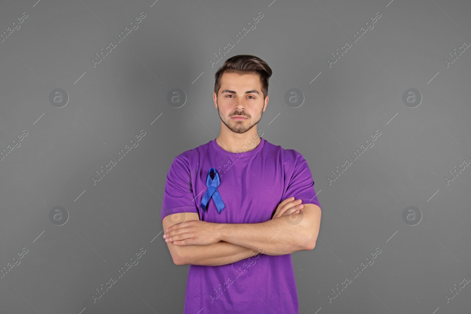 Photo of Young man with blue ribbon on grey background. Urological cancer awareness