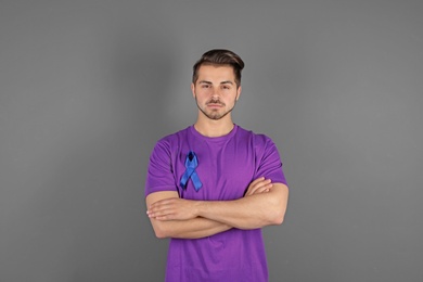 Photo of Young man with blue ribbon on grey background. Urological cancer awareness