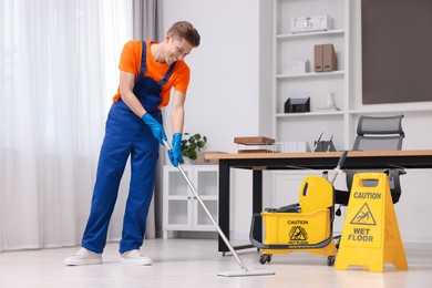 Photo of Cleaning service. Man washing floor with mop in office
