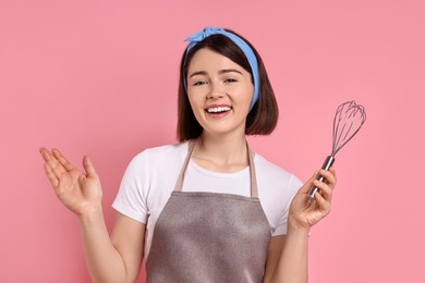 Photo of Happy confectioner with whisk on pink background