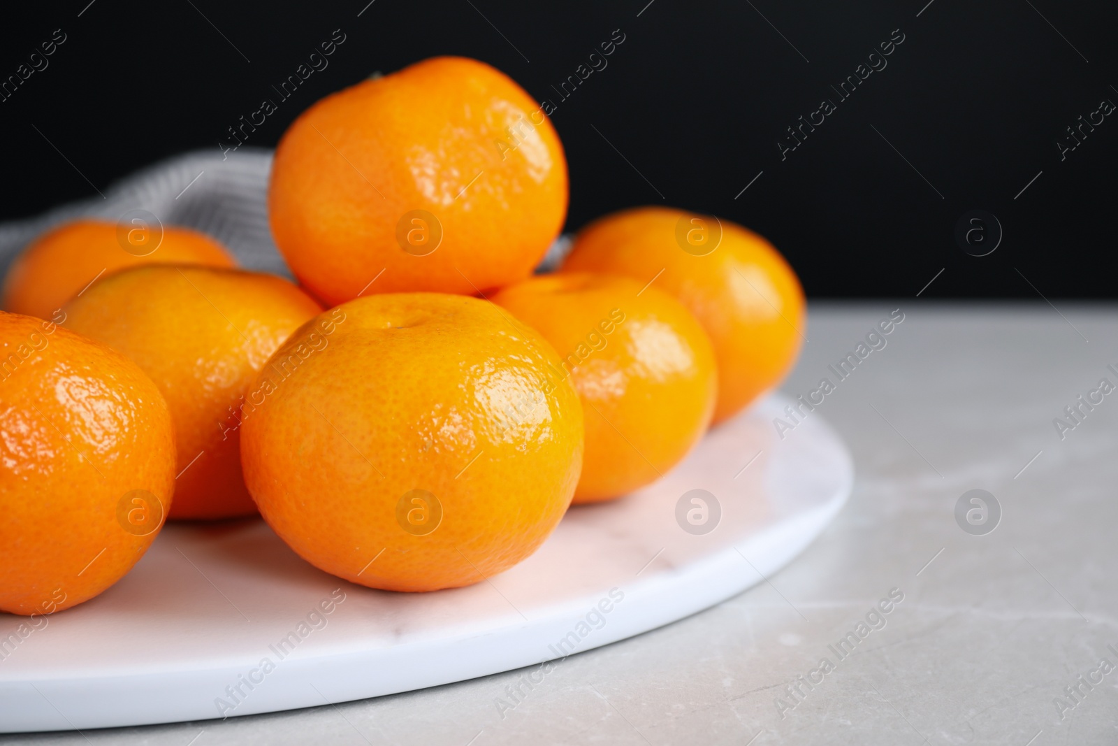 Photo of Fresh ripe tangerines on light grey table, closeup. Space for text