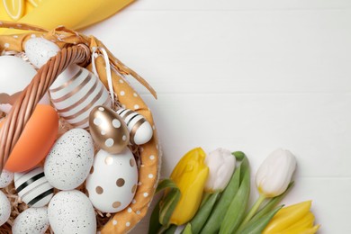 Photo of Flat lay composition with Easter eggs in basket and tulips on white wooden table. Space for text