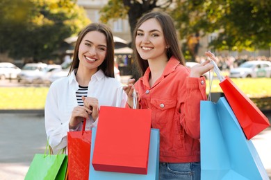 Photo of Beautiful young women with shopping bags on city street
