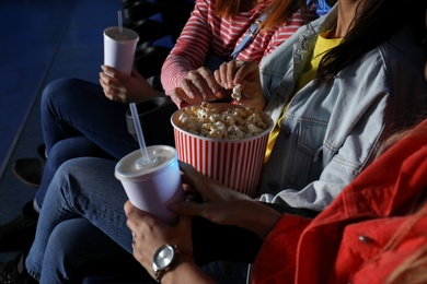 Photo of Young people eating popcorn during showtime in cinema theatre
