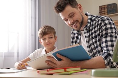 Photo of Dad helping his son with school assignment at home