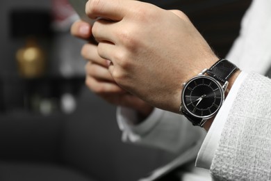 Photo of Businessman with luxury wrist watch on blurred background, closeup