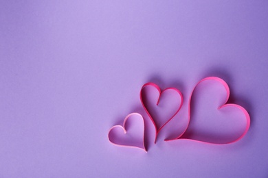 Photo of Hearts made of ribbons and space for text on color background, top view