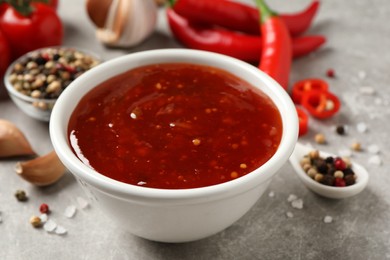 Photo of Spicy chili sauce in bowl on grey table, closeup