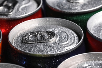 Photo of Aluminum cans of beverage covered with water drops as background, closeup