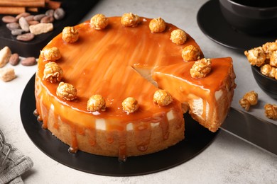 Photo of Delicious caramel cheesecake with popcorn on light grey table, closeup