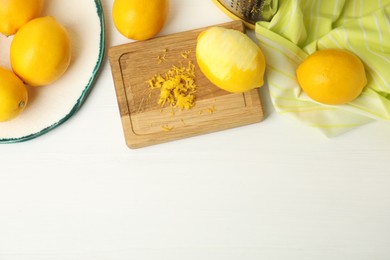 Photo of Lemon zest and fresh fruits on white wooden table, flat lay. Space for text