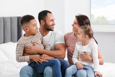 Photo of Happy international family spending time together on bed at home