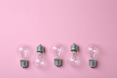 Photo of New incandescent lamp bulbs on pink background, top view. Space for text