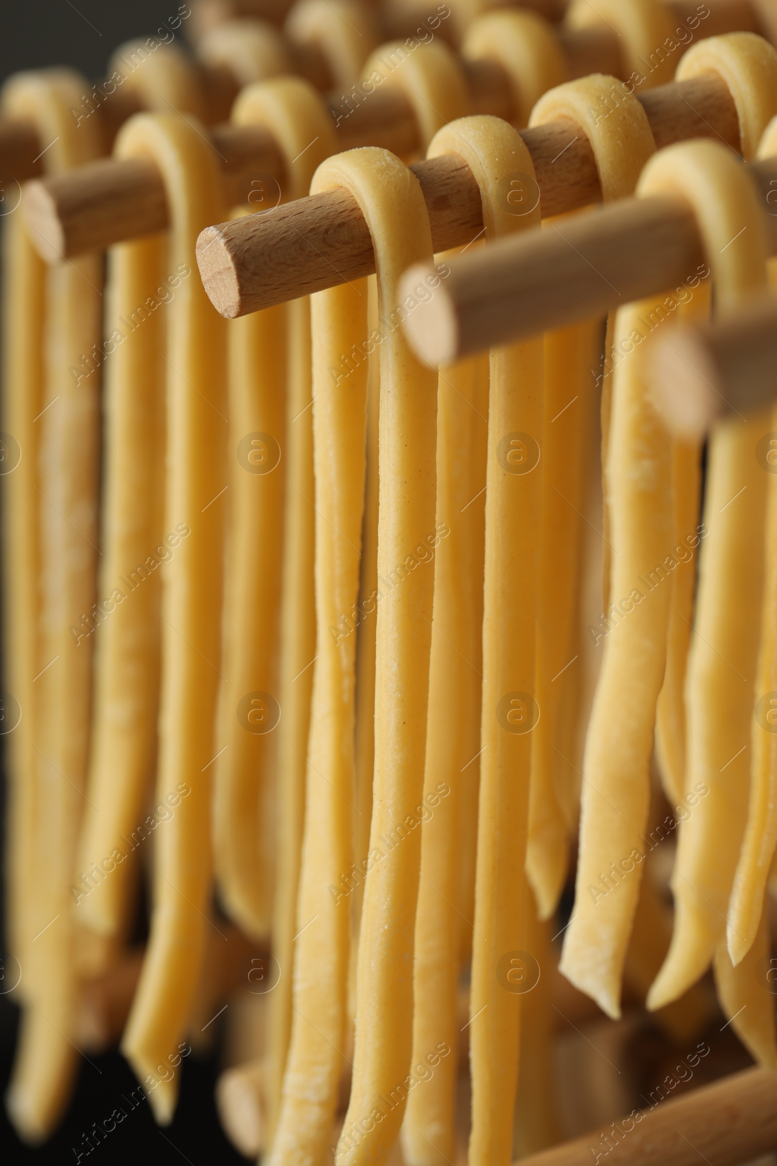 Photo of Homemade pasta drying on wooden rack, closeup