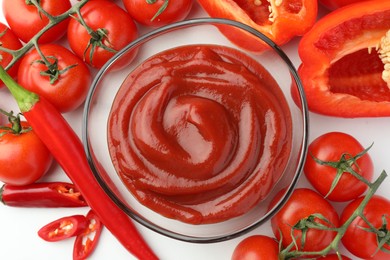 Photo of Bowl of tasty ketchup, tomatoes and peppers on white table, flat lay